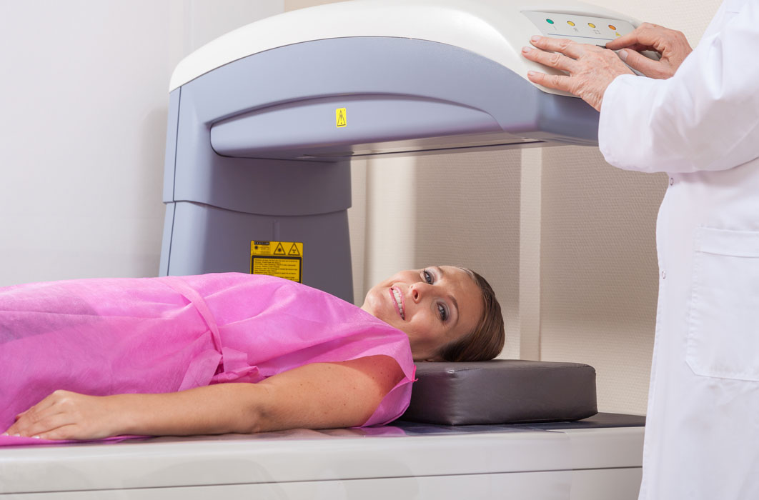 Smiling patient receiving a DEXA bone density or bone mineral densitometry exam